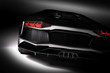 Black fast sports car in spotlight, black background. Shiny, new, luxurious.
