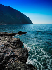 Vertical vivid stony beach tidal waves with ship landscape backg