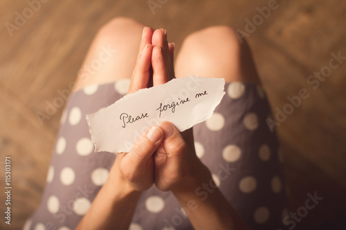 Fotografía Woman holding a paper note with the text please forgive me