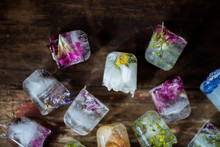 Frozen Flowers In Ice Cubes On Rustic Wooden Background