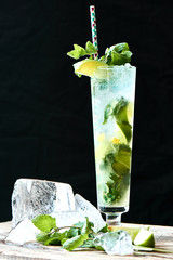 Wall Mural - Alcoholic cocktail Mojito in the glass and chunks of ice on a wooden table