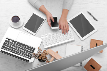 Canvas Print - Concept of using electronics. Businesswoman works at office, close up. Computer, laptop, tablet, cup of coffee and other things on the table. Top view