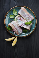 Wall Mural - Glass plate with herring fillet on a black wooden background