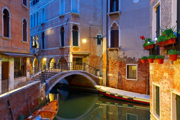 Wall Mural - Lateral canal and pedestrian bridge in Venice at night with street light illuminating bridge and houses, with docked boats, Italy