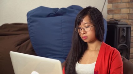Poster - Happy young asian woman sitting in the room with stereo listen music and chatting online in social net at home. Female using internet for communication. Girl with long black hair can be student, work
