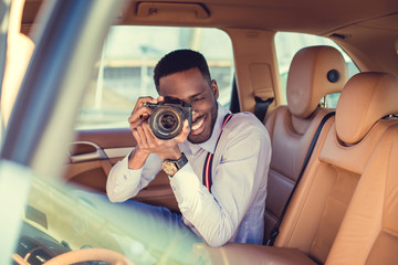 Wall Mural - A black man using dslr camera in a car.