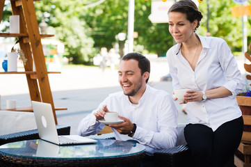 Business colleagues with a laptop working in outdoors cafe using conference internet call