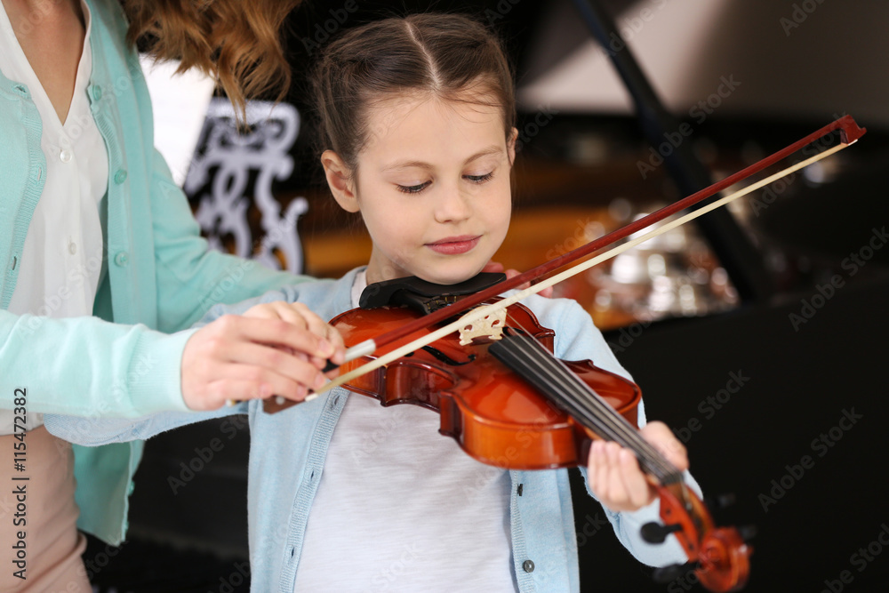 Small girl learning play violin with teacher