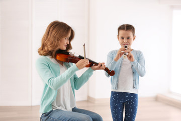 Poster - Two girls playing violin and flute on light background