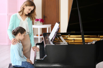 Wall Mural - Small girl learning play piano with teacher