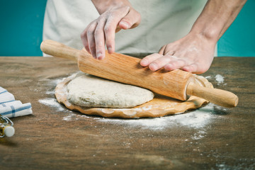 Making dough by mens hands on wooden table background