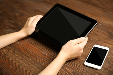 Poster - Mobile phone and female hands using tablet, on the wooden background