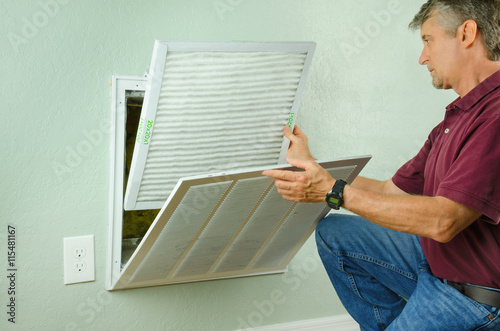 Fotomural Professional repair service man or diy home owner a clean new air filter on a house air conditioner which is an important part of preventive maintenance