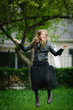 © BSstudio - smiling young teenage girl jumping over green park background dressed black leather jacket