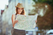 © baranq - Attractive young woman reading map in the city