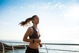 Picture of young attractive fitness girl jogging with sea on background