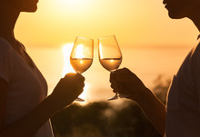 Young Couple Enjoying A Glass Of Wine On The Beach. Vacation And Holiday Concept.

