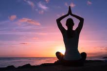 Young Healthy Woman Practicing Yoga On The Beach At Sunset

