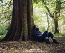 Sweden, Skane, Stenshuvud Nationalpark, Woman Sitting Under Tree