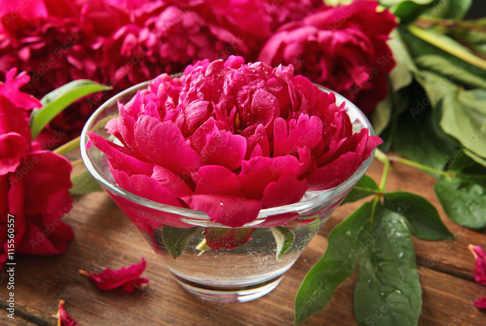 Beautiful peony in glass on wooden background