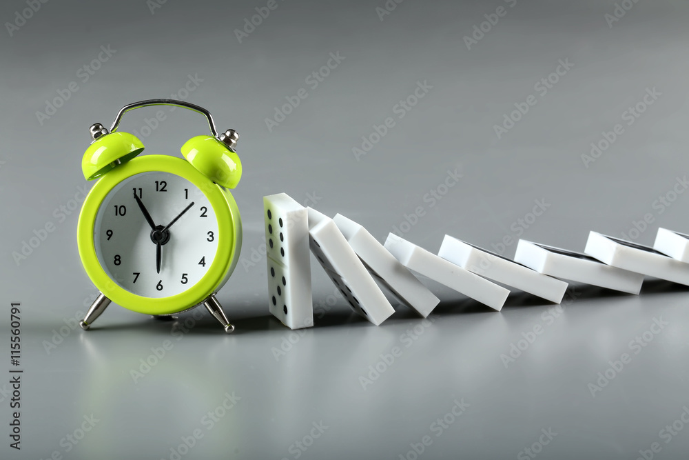 Dominoes and alarm clock on grey background