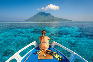 Sticker - Young woman in swimsuit sit on boat with a mask and flippers loo