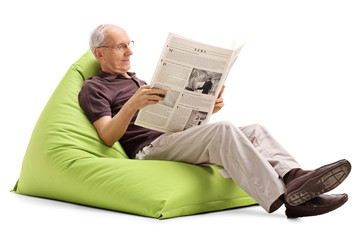 Poster - Senior reading the news seated on beanbag