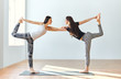 © GVS - Two young women doing yoga asana lord of the dance pose