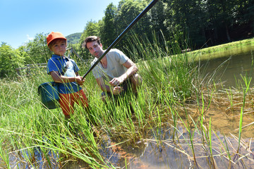 Wall Mural - Little boy learning how to fish with his dad