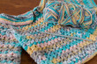 Handmade crocheted baby sweater with yarn and hook
