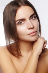 Wall Mural - Beautiful young woman with clean face, shiny skin, fashion natural make-up, perfection eyebrows. Cute bun hairstyle. Spa portrait, naturel cosmetics, healthy fresh look