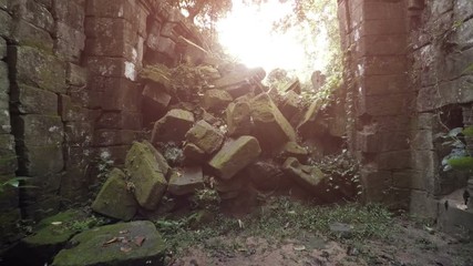 Wall Mural - Ancient and enormous, moss covered stone blocks of a collapsed wall, overgrown with vines at a temple ruin in Cambodia. Video 3840x2160