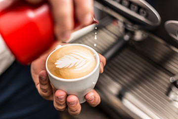 Wall Mural - Closeup of barista pouring milk into art cappuccino