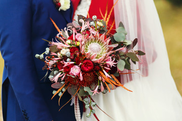 A closeup of a rich wedding bouquet made of autumn flowers and h