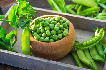 Wall Mural - Bowl with fresh peas on a wooden background