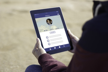 Man sitting on the beach and using his social network profile