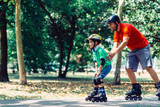 Father and son roller skating in park, spending quality time
