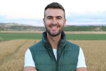 Young happy man smiling at camera in the potato and wheat fields