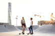 Teenage girls with skateboards at skate park, Turning Torso in background