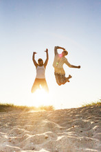 Young Couple Jumping On Beach