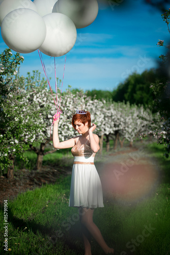 A Charming Girl In The Green Garden With Balloons Tied To Her Hand