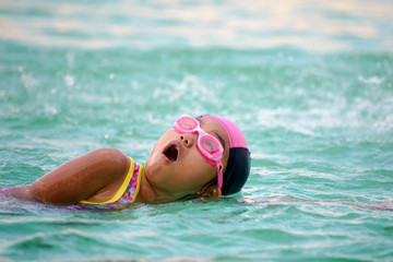 Little cute girls deftly swim in pool