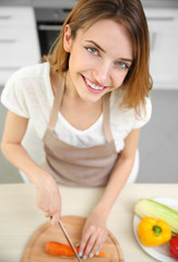 Wall Mural - Beautiful girl cutting vegetables in kitchen