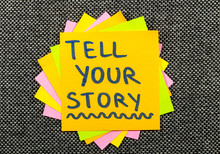 Tell Your Story Suggestion On A Sticky Note Against Fabric Texture