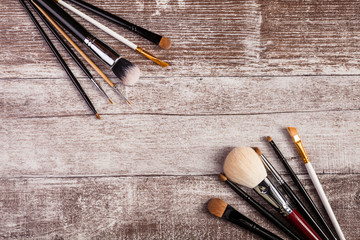 Make up brushes in on top view image on wooden background