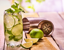 Alcohol Drink. On Wooden Boards Three Glasses With Alcohol Drink And Ice Cubes. Drink Hundred Fifty Five Cocktail Mohito With Cocktail Metal Shaker And Mint . Country Still Life. Light Background.