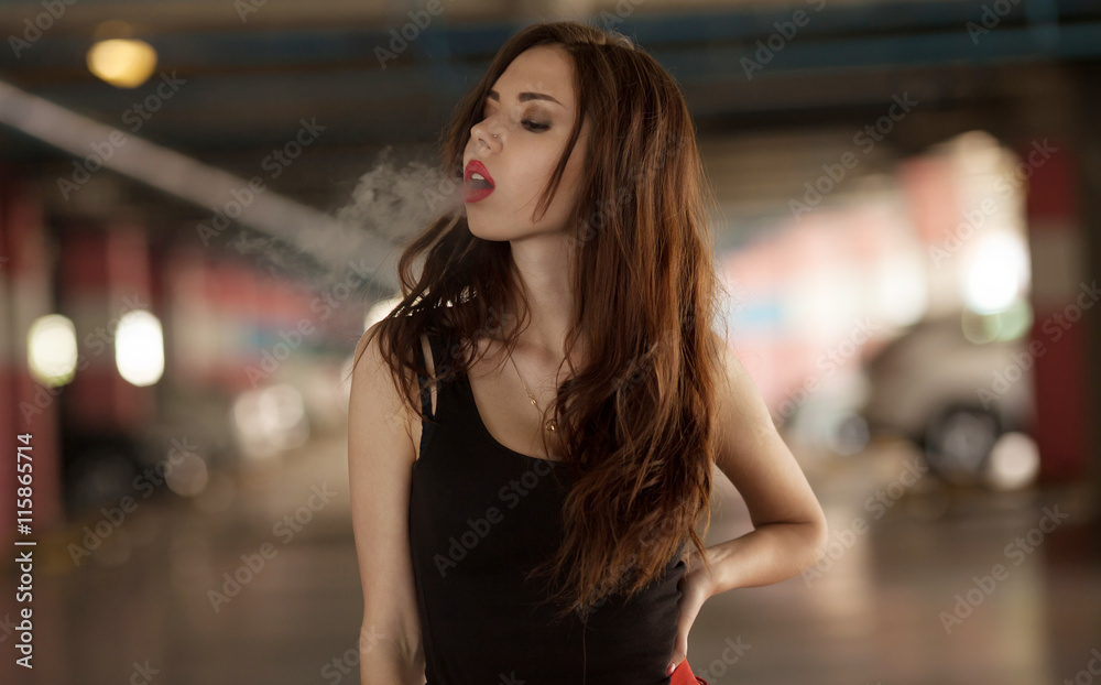 Photo Stock Young beautiful woman smoking ( vaping ) e-cigarette with smoke 
