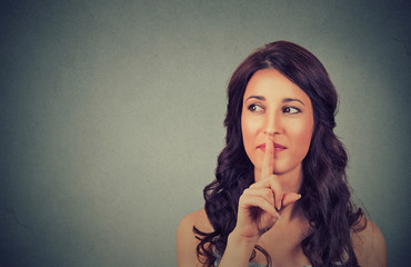 Portrait of attractive teenage girl with finger on lips, concept of student show quiet, silence, secret gesture, young pretty brunette woman