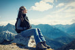 Frau bei Berg Wanderung macht Rast, sitzt auf einem Stein und schaut ins Tal