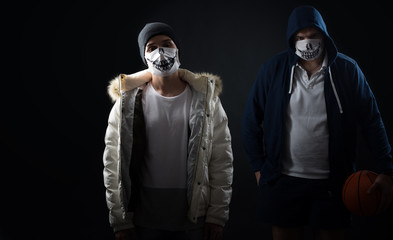 studio on a black background portrait of two men in masks with basketball